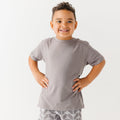 Child wearing a gray t-shirt and geometric-patterned shorts on a white background