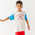 Child wearing a white t-shirt with blue sleeves and red shorts on a white background