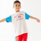 Child wearing a t-shirt with 'Home of the Brave' text and American flag design on a white background