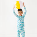 Child wearing a palm tree patterned pajama set holding a beach ball.
