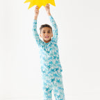 Child wearing a blue palm tree patterned pajama set holding a yellow star-shaped object.