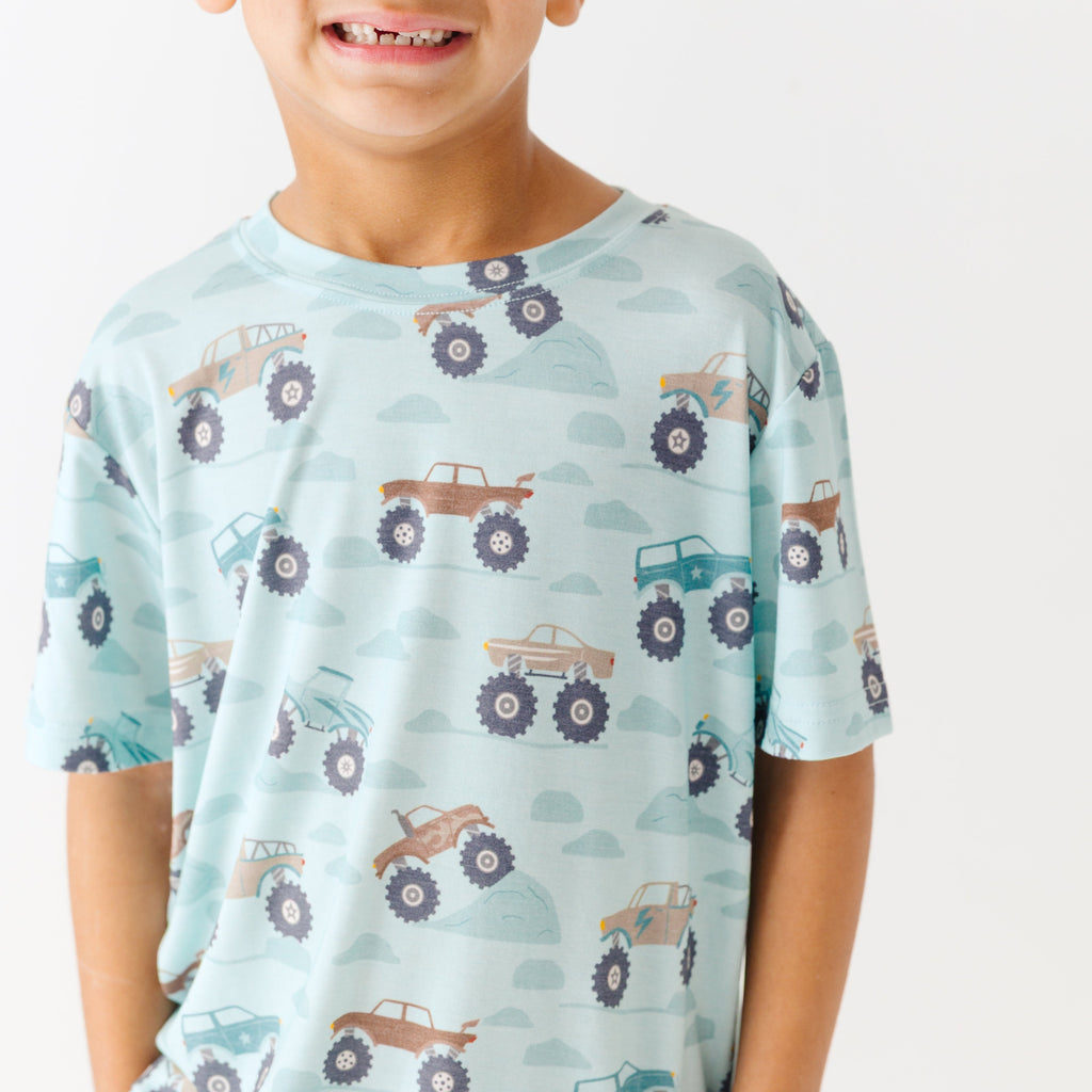 Close up shot of a child wearing a light blue t-shirt with vehicle pattern on a white background