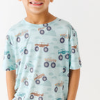 Close up shot of a child wearing a light blue t-shirt with vehicle pattern on a white background