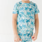 Child wearing a blue palm tree patterned pajama on a white background