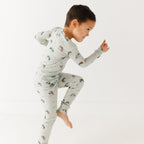 Child wearing a long sleeve pajama set with vehicle patterns on a white background