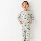 Child wearing a long sleeve pajama set with vehicle patterns on a white background
