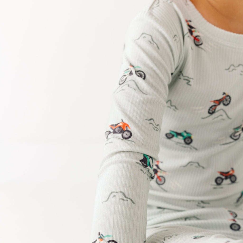 Close up shot of a child wearing a long sleeve pajama with vehicle patterns on a white background