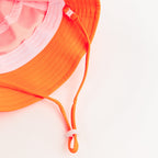 Orange bucket hat with a strap on a plain background