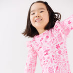 Child wearing a pink and white patterned long sleeve one-piece swimsuit on a white background