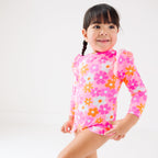 Child wearing a pink floral one-piece swimsuit on a white background