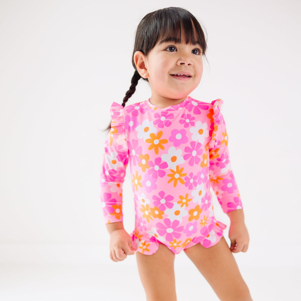 Child wearing a pink floral one-piece swimsuit on a white background