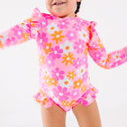 Close up shot of a child wearing a pink floral one-piece swimsuit on a white background
