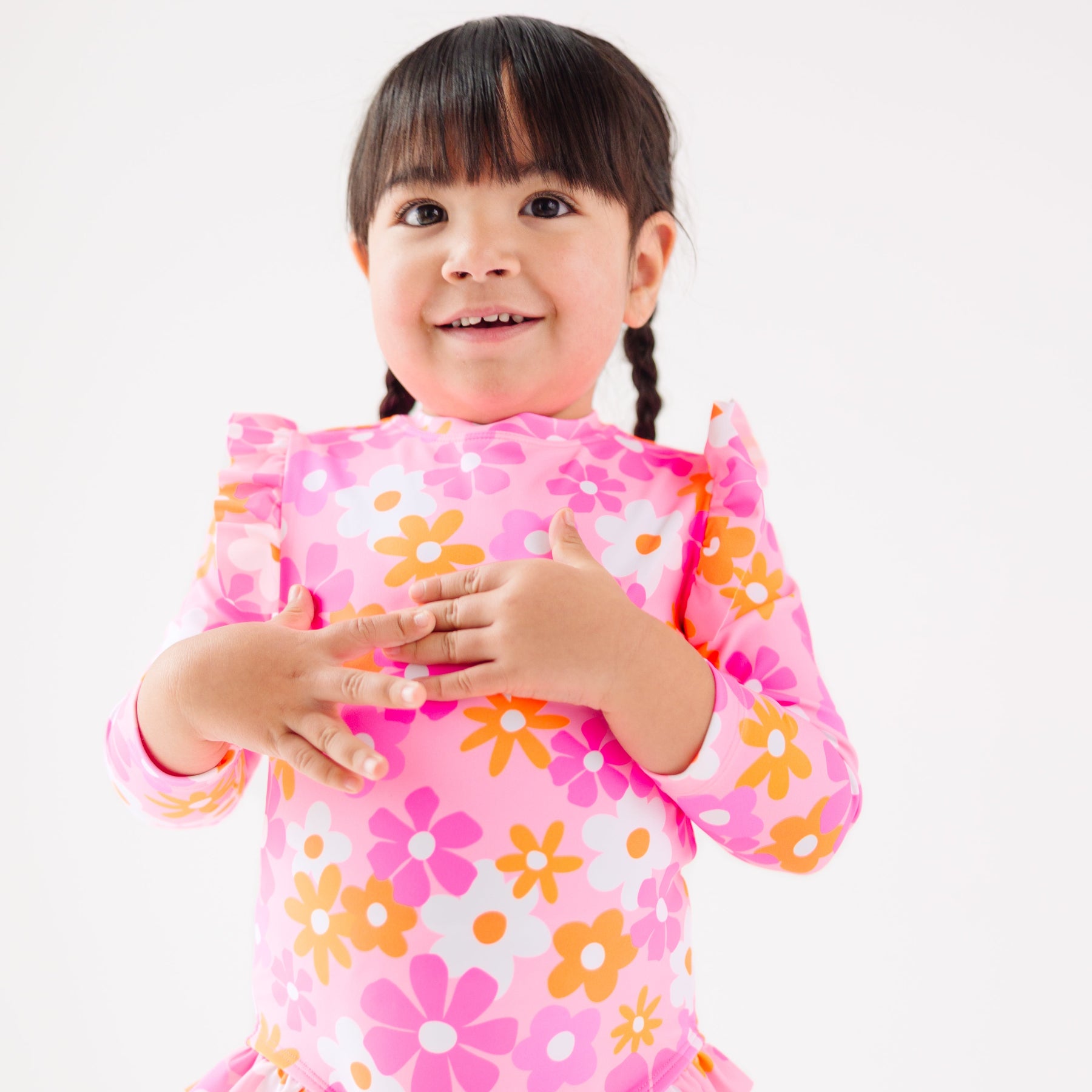 Child wearing a pink floral one-piece swimsuit on a white background