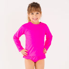 Child wearing a bright pink long sleeve two-piece swimsuit on a white background