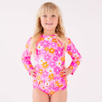 Child wearing a pink floral two-piece swimsuit on a white background