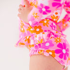 Close up shot of a child wearing a pink floral two-piece swimsuit