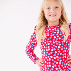 Young girl wearing a red floral swimsuit on a white background