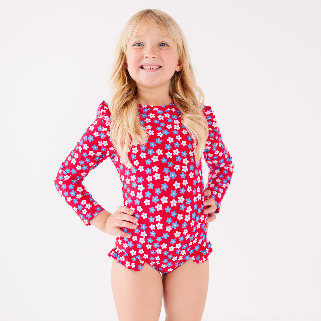 Young girl wearing a red floral swimsuit on a white background