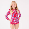Young girl wearing a red floral swimsuit on a white background