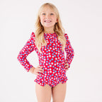 Young girl wearing a red floral swimsuit on a white background