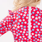 Close up of a young girl's back view wearing a red floral swimsuit on a white background