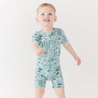 Child wearing a blue short romper with summer patterns on a white background