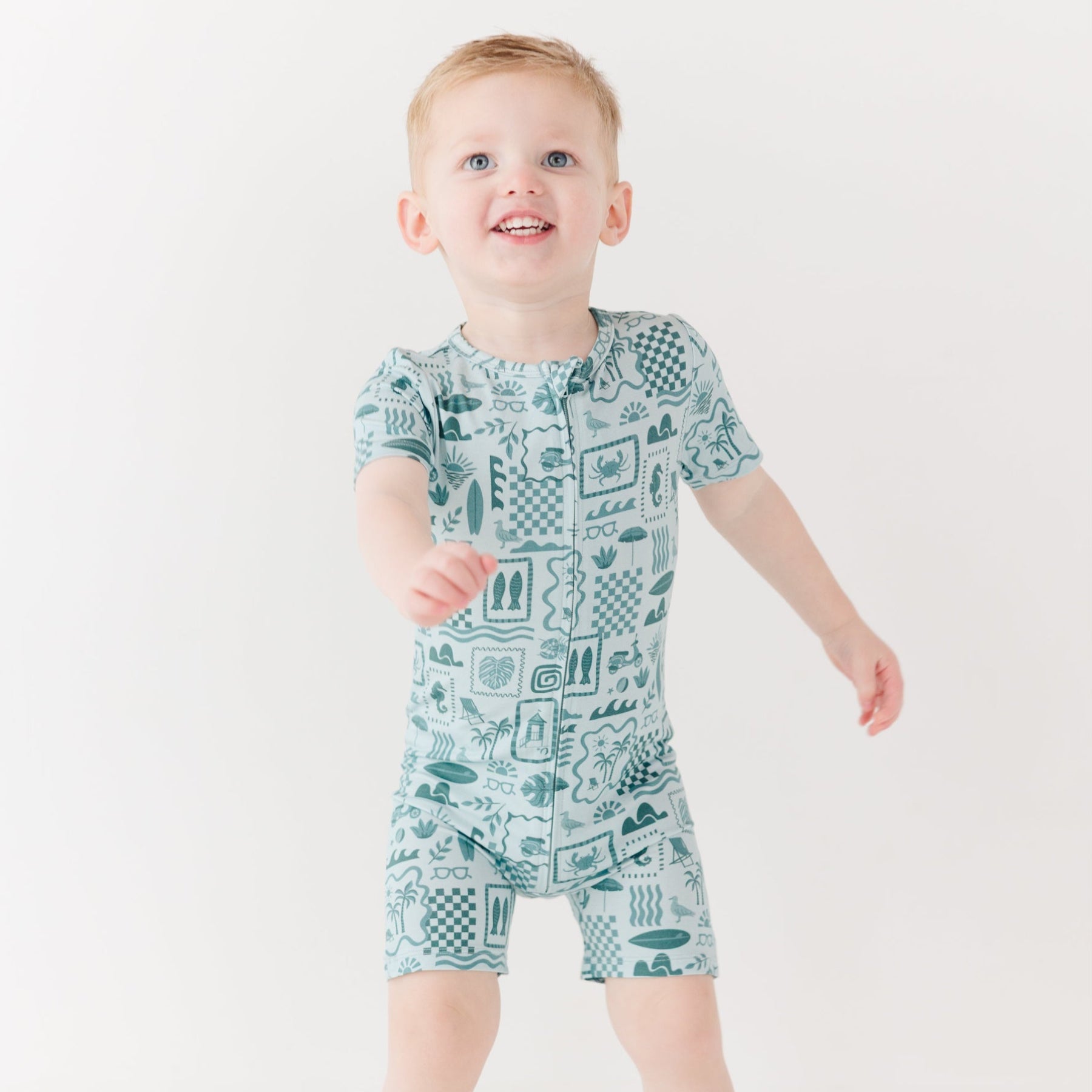 Child wearing a blue short romper with summer patterns on a white background