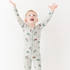 Child wearing a long-sleeve onesie with vehicle patterns on a white background