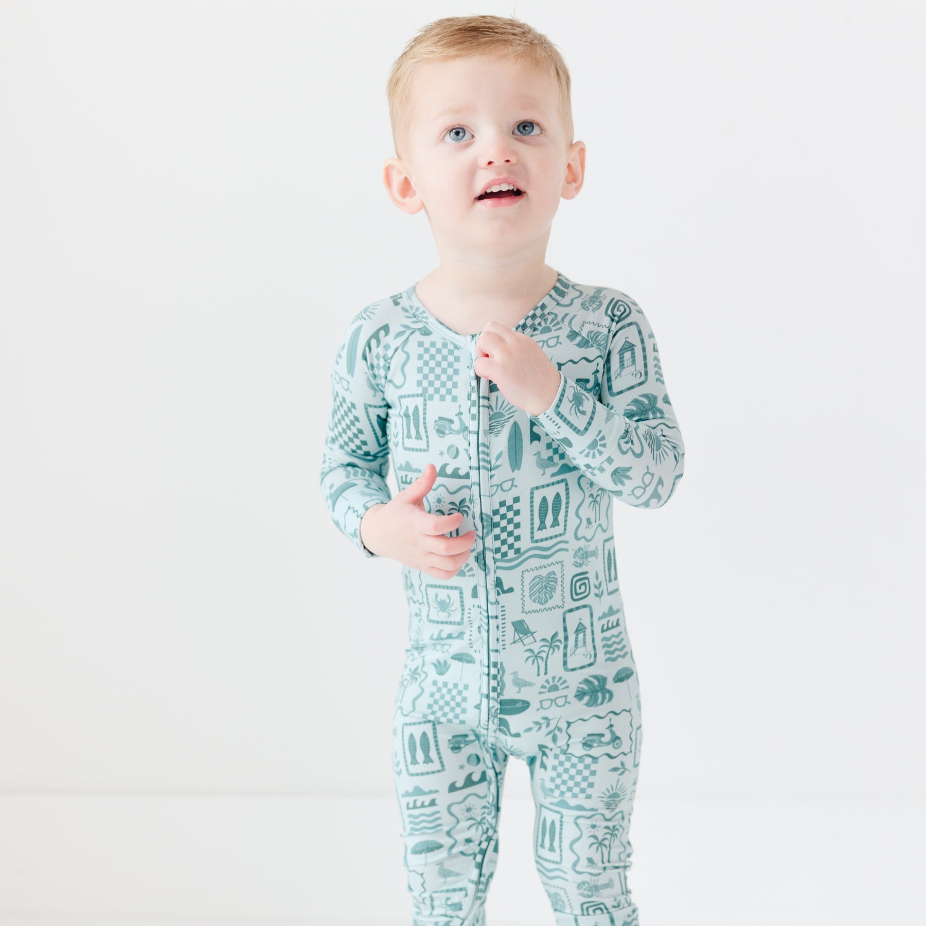 Child wearing a blue summer-patterned onesie on a white background
