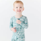 Child wearing a blue summer-patterned onesie on a white background