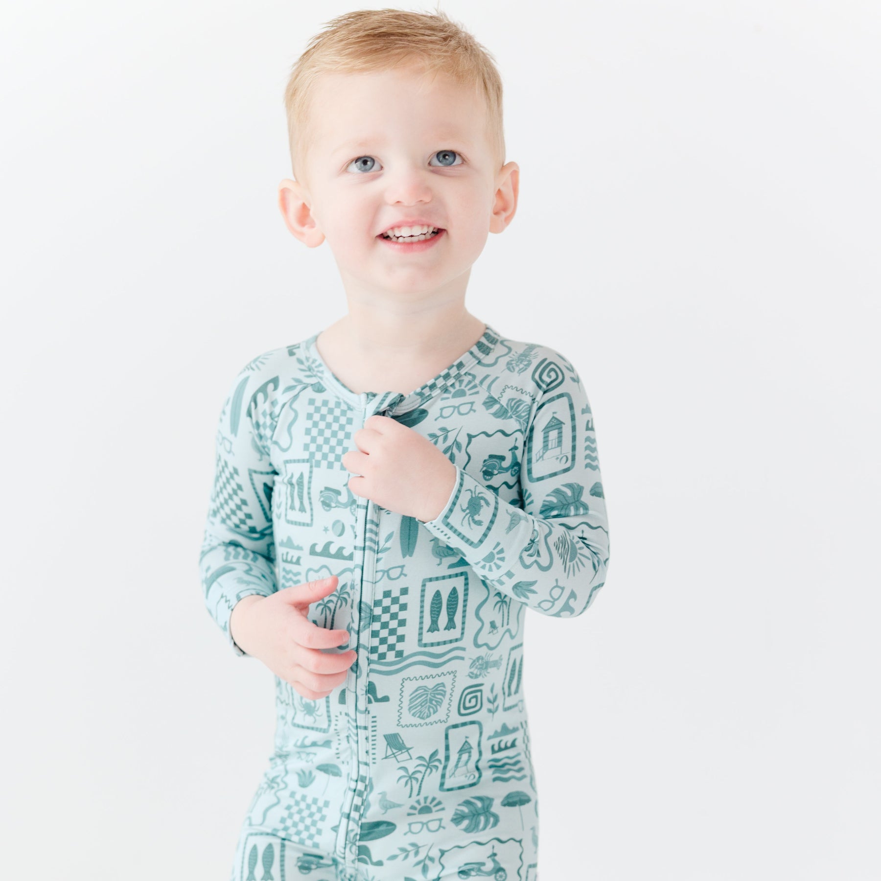 Child wearing a blue summer-patterned onesie on a white background