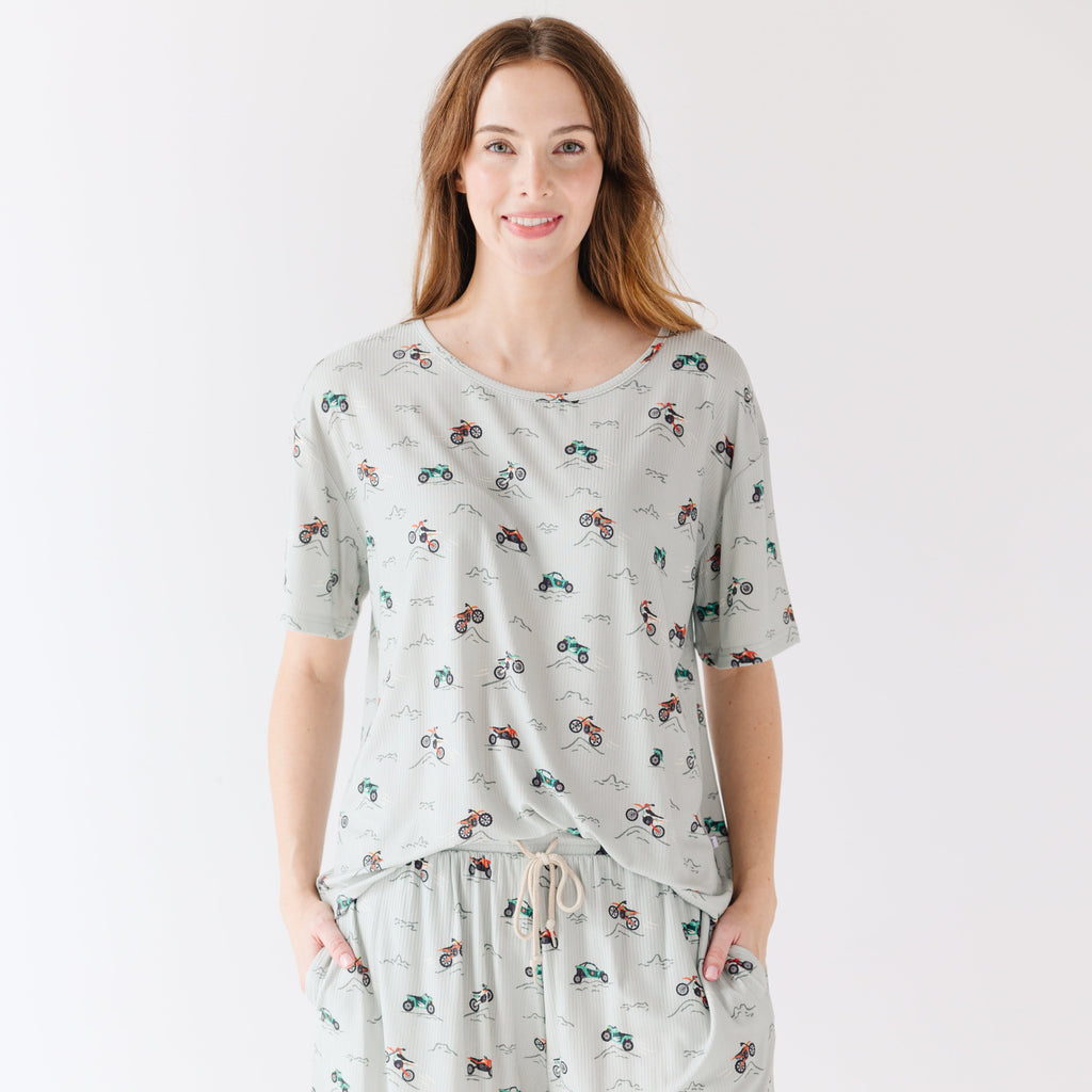 Woman wearing a light gray pajama set with vehicle patterns on a white background