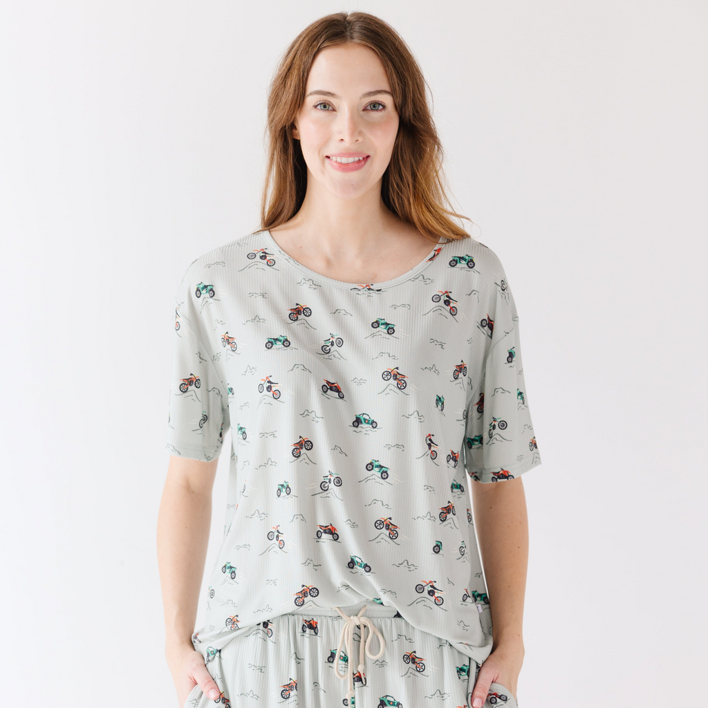 Woman wearing a light gray pajama set with vehicle patterns on a white background
