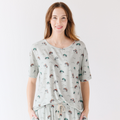 Woman wearing a light gray pajama set with vehicle patterns on a white background