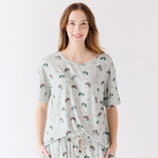 Woman wearing a light gray pajama set with vehicle patterns on a white background