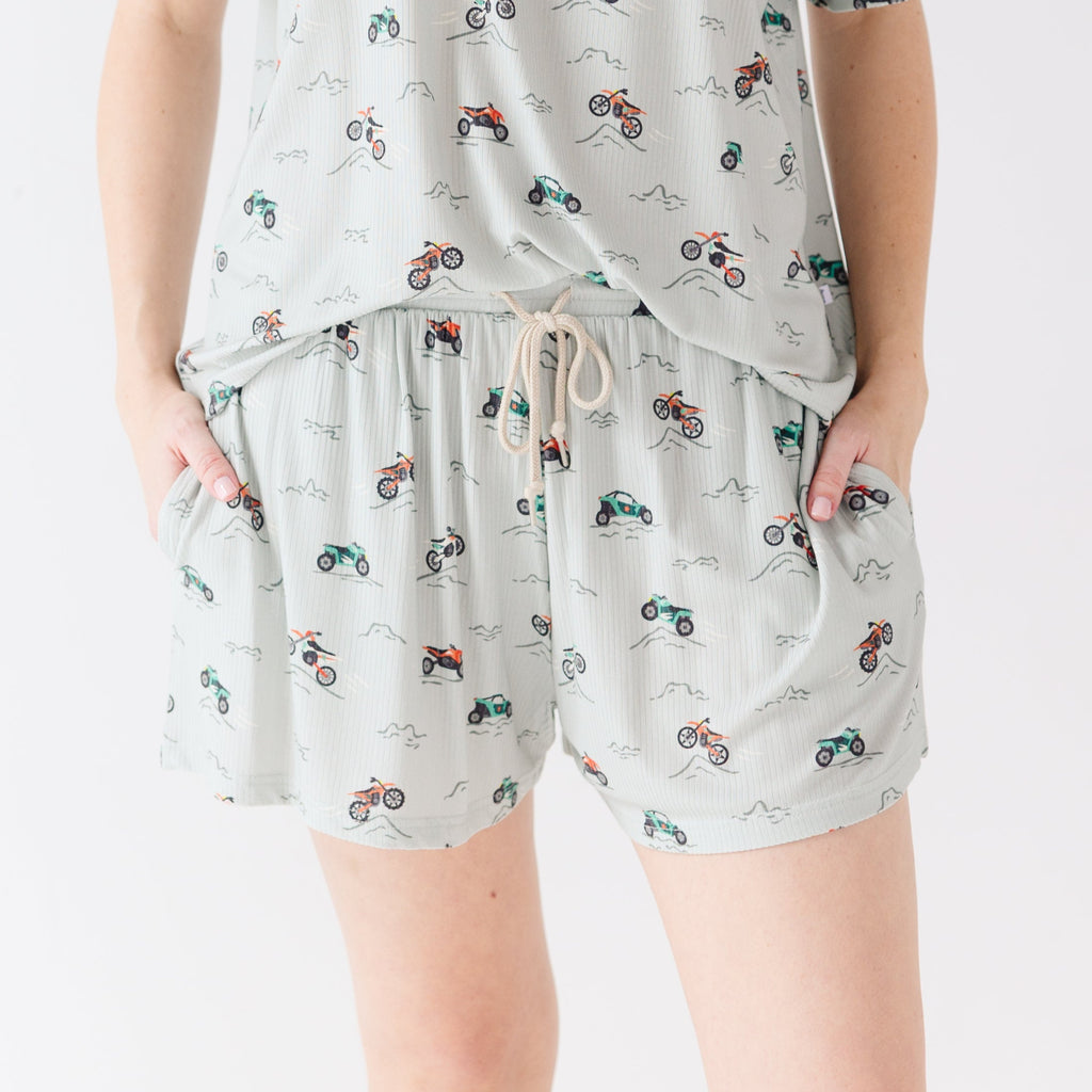 Woman wearing a light gray pajama shorts with vehicle patterns on a white background
