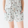 Woman wearing a light gray pajama shorts with vehicle patterns on a white background