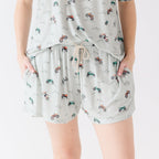 Woman wearing a light gray pajama shorts with vehicle patterns on a white background