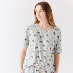Woman wearing a light gray pajama set with vehicle patterns on a white background