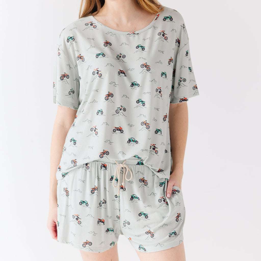Woman wearing a light gray pajama set with vehicle patterns on a white background