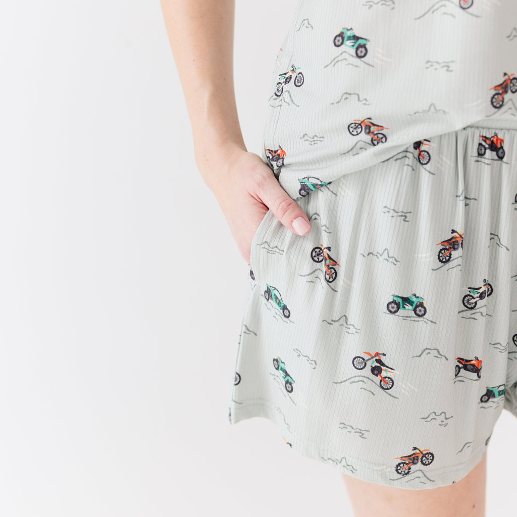 Close up shot of a woman wearing a light gray pajama shorts with vehicle patterns on a white background