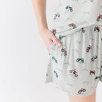 Close up shot of a woman wearing a light gray pajama shorts with vehicle patterns on a white background