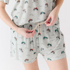 Close up shot of a woman wearing a light gray pajama shorts with vehicle patterns on a white background