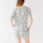 Back view of a woman wearing a light gray pajama set with vehicle patterns on a white background