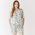 Woman wearing a light gray pajama set with vehicle patterns on a white background