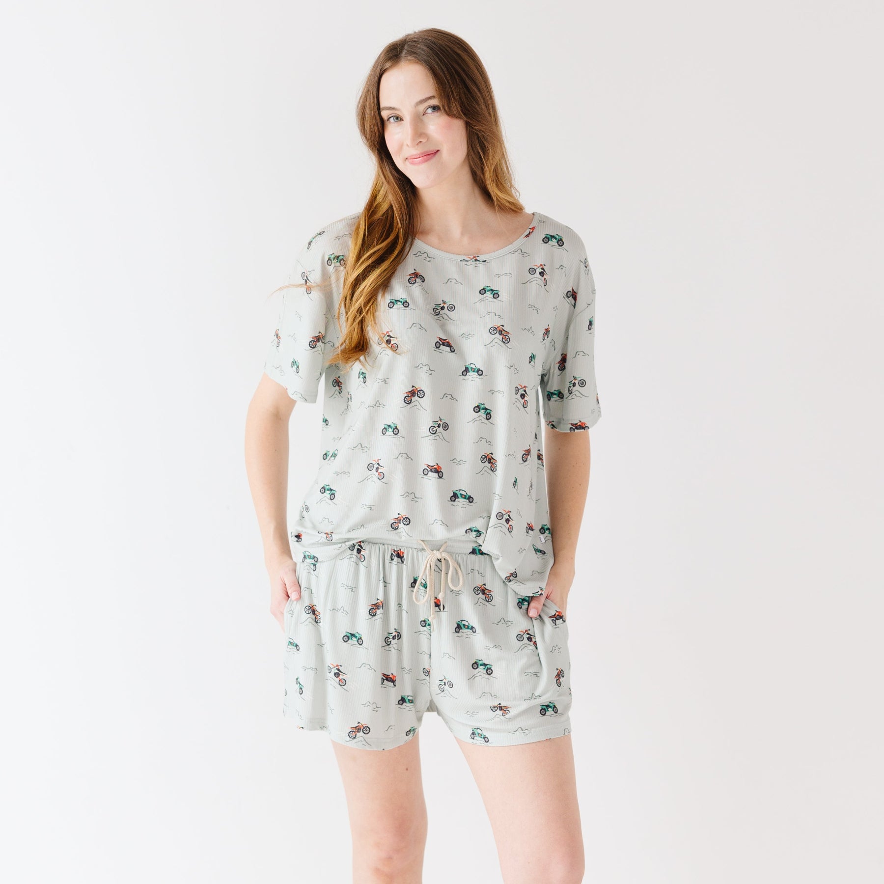 Woman wearing a light gray pajama set with vehicle patterns on a white background