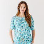 Woman wearing a blue palm tree patterned pajama on a white background