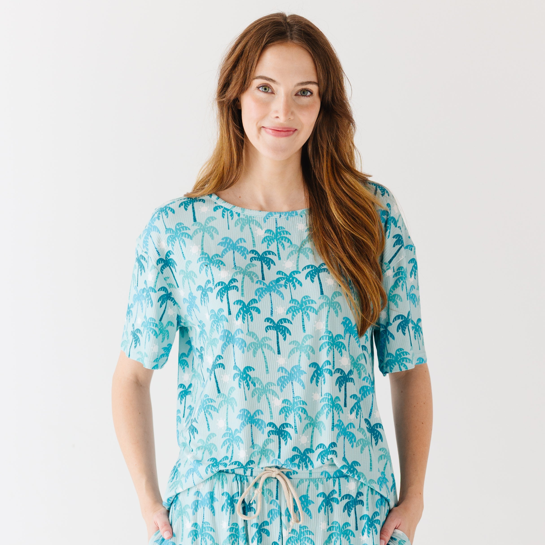 Woman wearing a blue palm tree patterned pajama on a white background