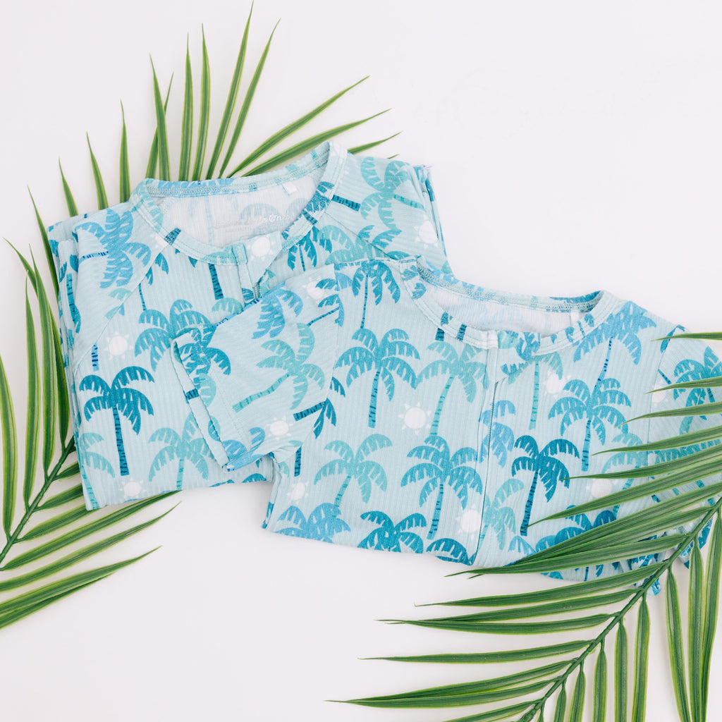 Set of blue palm tree patterned pajamas with green leaves on a white background