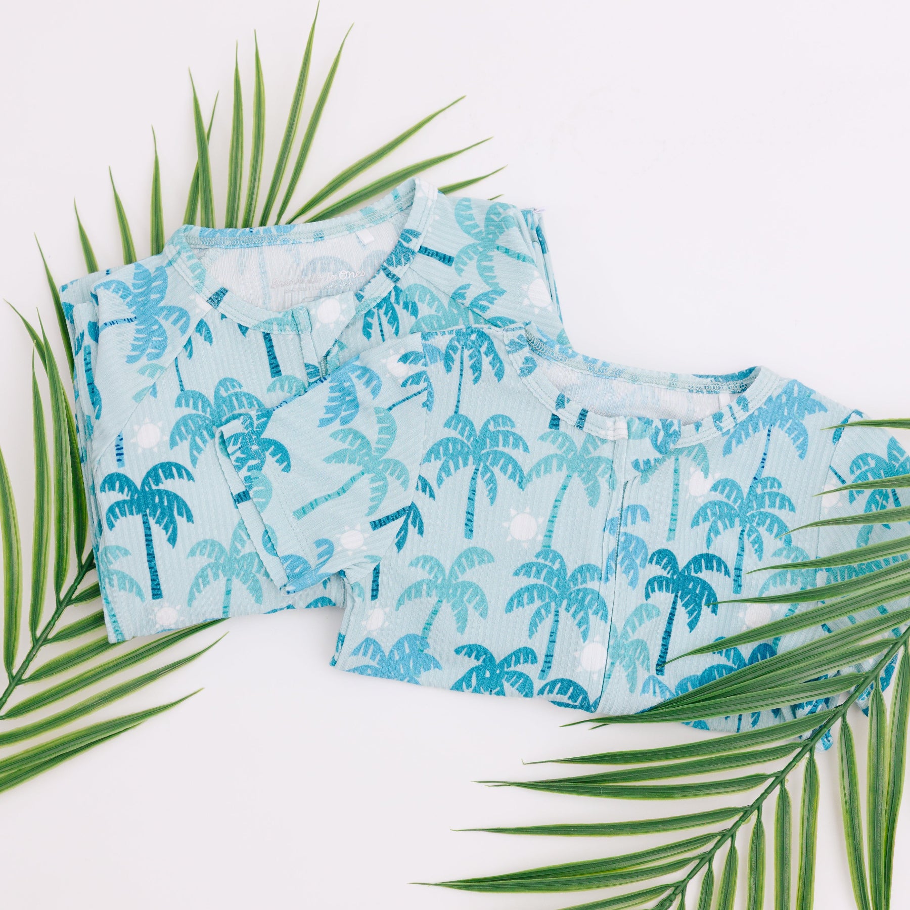 Set of blue palm tree patterned pajamas with green leaves on a white background